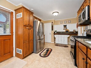 Una cocina con armarios de madera, un refrigerador de acero inoxidable, una estufa y un microondas.
