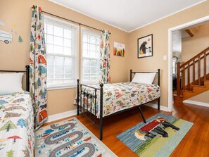 Un dormitorio con dos camas, una ventana con persianas, una puerta y una escalera.