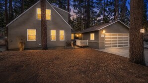 A two-story house with a garage, surrounded by tall trees and a well-maintained lawn. - Country Bear Inn - Game Room, Pool Table, Barbecue (Big Bear City)
