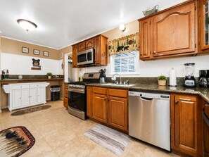 A kitchen with wooden cabinets, stainless steel appliances, a microwave, a stove, and a dishwasher.