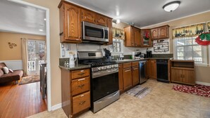 Una cocina con armarios de madera, electrodomésticos de acero inoxidable y un tapete con estampado rojo y blanco.