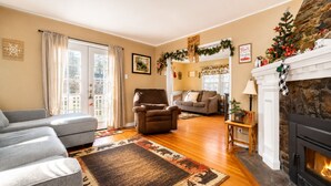 A living room with a fireplace, a sofa, a chair, and a rug. - Country Bear Inn - Game Room, Pool Table, Barbecue (Big Bear City)