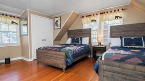 Un dormitorio con dos camas de madera, una ventana con cortinas, una puerta y un cuadro colgado en la pared.