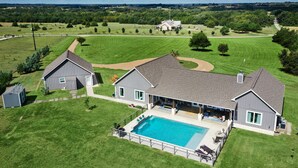 Ein großes Haus mit Swimmingpool, umzäunter Garten und gepflegtem Rasen.
