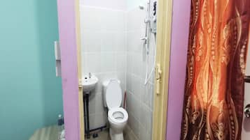 A small bathroom with a toilet, sink, and shower.