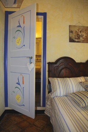 Una habitación con una cama, una puerta decorada y un cuadro en la pared.
