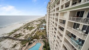 A high-rise hotel with multiple balconies overlooking a beach and a pool area. - Beach Club 1603A - Lil Bit of Paradise is your perfect beach getaway (Gulf Shores)