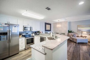 Una cocina moderna con electrodomésticos de acero inoxidable, una isla central y un comedor con sofá y lámpara.