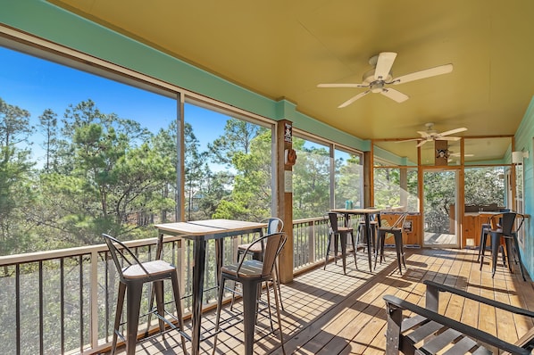 A covered outdoor area with tables and chairs, large windows, and ceiling fans.