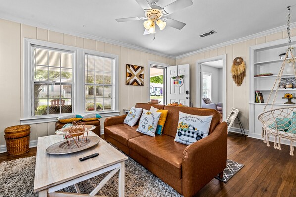 A cozy living room with a brown leather sofa, a coffee table, and a ceiling fan.