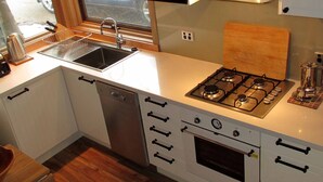 A compact kitchen with a gas stove, oven, sink, and a dishwasher. - Wallace's-Chalet (Dinner Plain)
