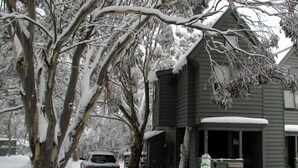 A house with a snow-covered porch and a snowman decoration. - Wallace's-Chalet (Dinner Plain)