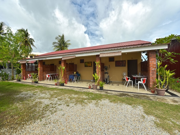 A building with a covered patio area, outdoor seating, and potted plants.