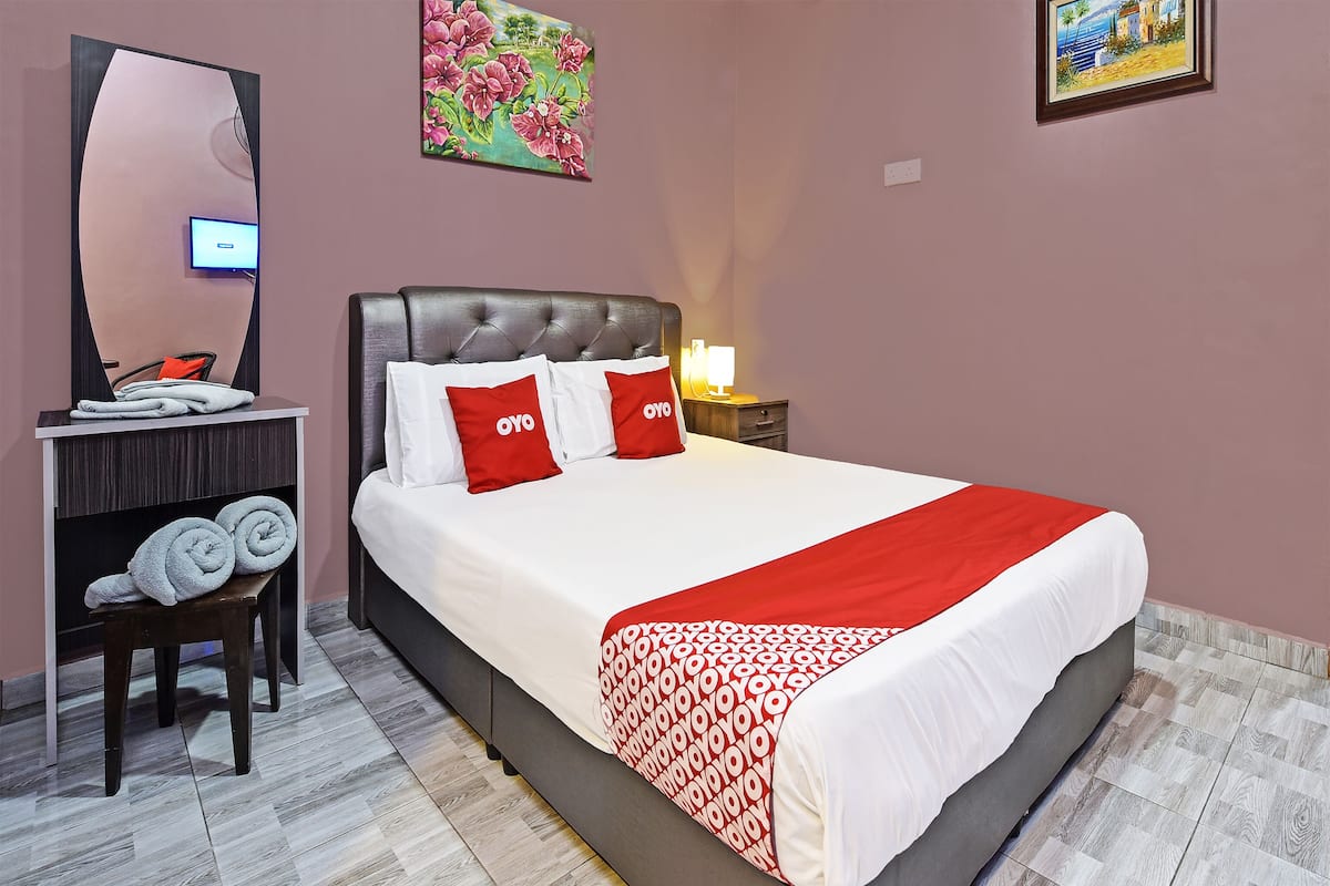 A hotel room with a bed, a desk with a computer, a chair, a mirror, and artwork on the walls.