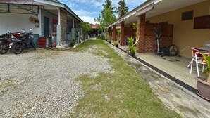 A residential street with houses, a gravel path, and potted plants. - Hotel O Inspire Rooms (Langkawi)