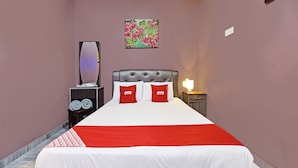 A neatly made bed with a red and white bedspread, two pillows with 'OYO' branding, a nightstand with a lamp, and a painting on the wall. - Hotel O Inspire Rooms (Langkawi)