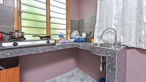 A compact kitchen with a gas stove, a sink, and a window with blinds. - Hotel O Inspire Rooms (Langkawi)