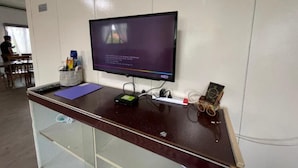 Un comptoir d’accueil avec un écran d’ordinateur affichant du texte, un organiseur de bureau et un petit objet décoratif.