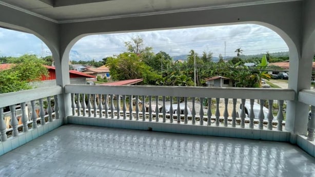 Un balcon doté d’un sol carrelé et d’une balustrade blanche.
