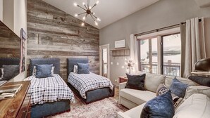 Une chambre avec deux lits, un canapé, un mur décoratif en bois et une grande fenêtre.