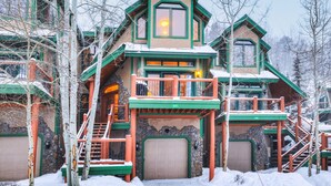 Un grand bâtiment à plusieurs étages, de style chalet, avec une façade en pierre, de nombreux balcons et un escalier imposant.