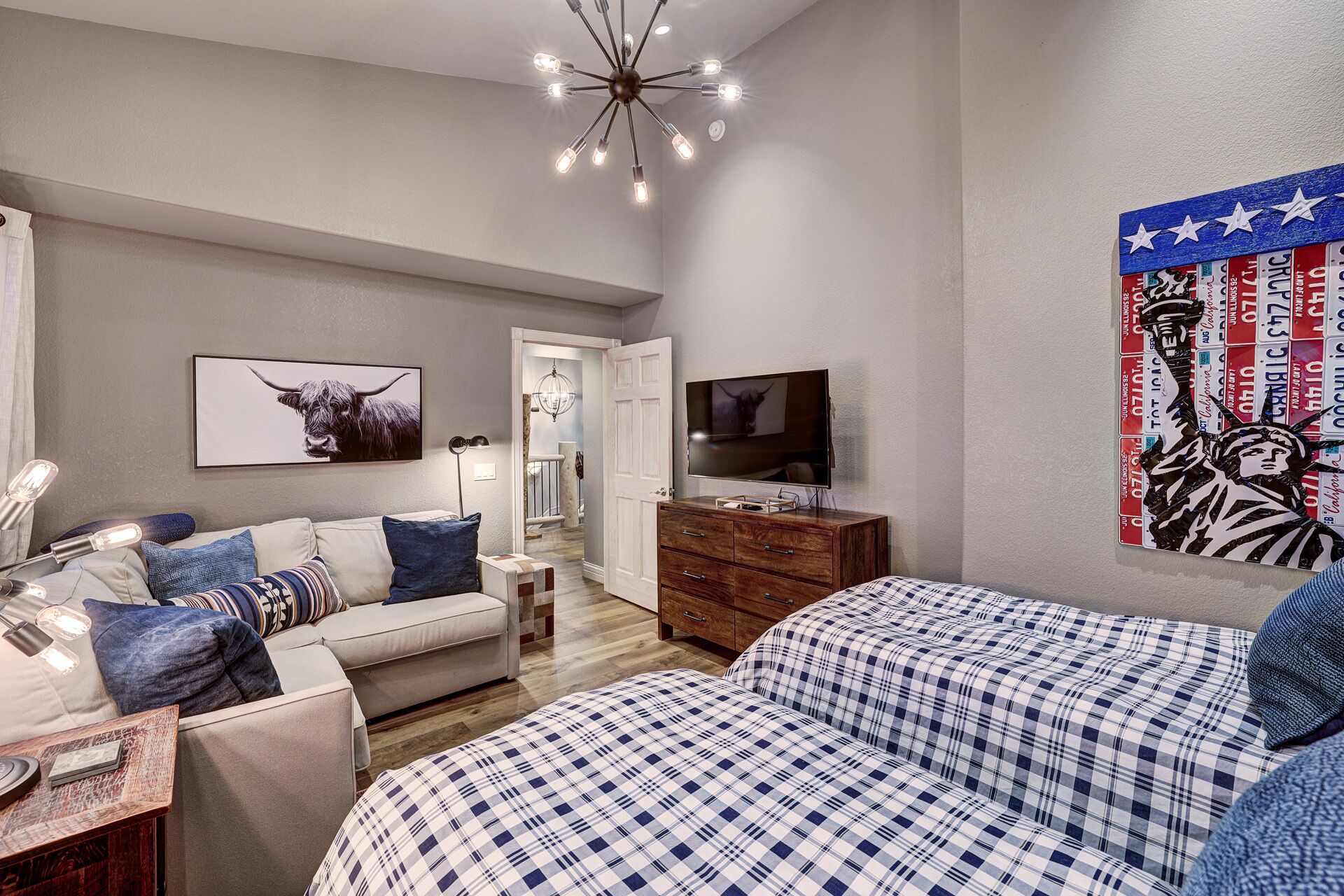 Un dormitorio moderno con una cama, un televisor, un tocador y una obra de arte en la pared.