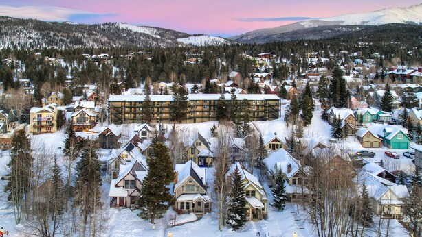 A snow-covered residential area with houses and a lodge.