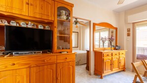 A wooden cabinet with a television, a glass-fronted display case, and a mirror.