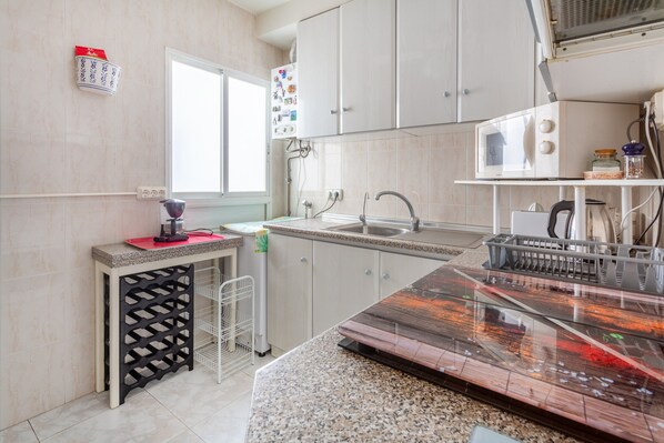 Una cocina con encimera de granito, un fregadero, armarios y un microondas.