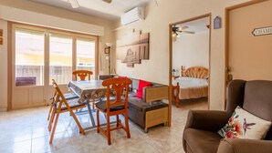 A dining area with a table, chairs, and a sofa. There is a ceiling fan, a wall-mounted air conditioner, and a door labeled 'CHAMBER'.