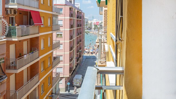 A multi-story building with balconies, a beach view, and a clear sky.