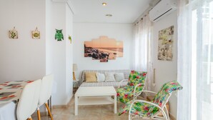 A room with a dining table, chairs, a sofa, and a chair with a floral pattern.