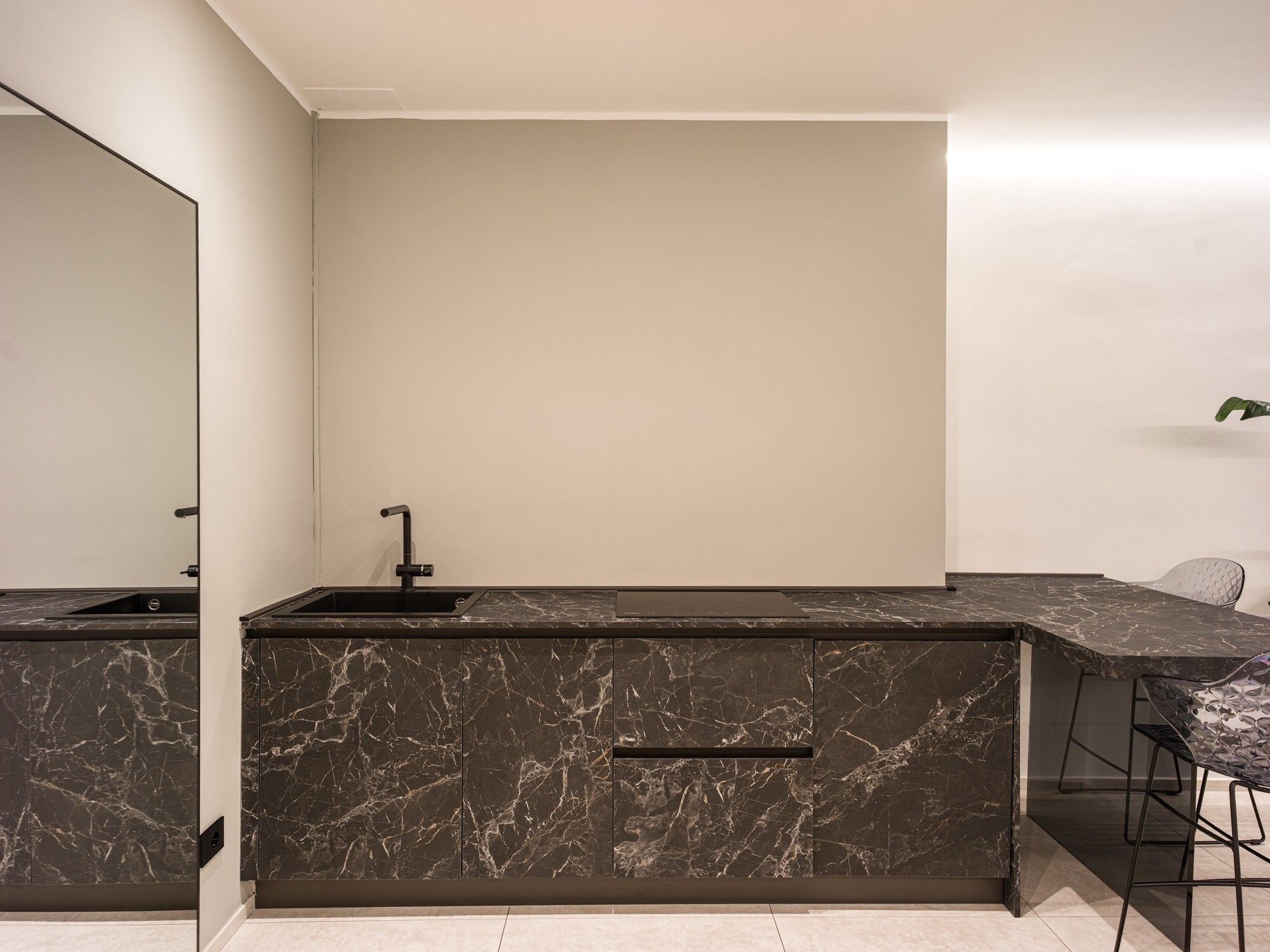 A modern kitchen with a marble countertop, a sink, and a bar area.