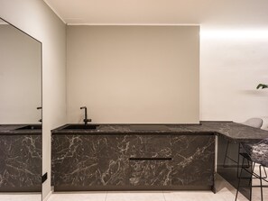 Eine moderne Küche mit Marmorarbeitsplatte, Spüle und einer Bar.