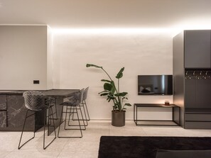 Eine moderne Küche mit Essbereich, einem Blumentopf, einem Fernseher und einem Einbauofen.