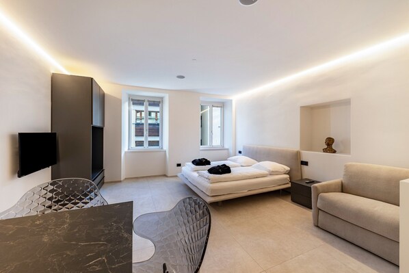 Une chambre moderne avec un lit, un canapé, une télévision et une table à manger.