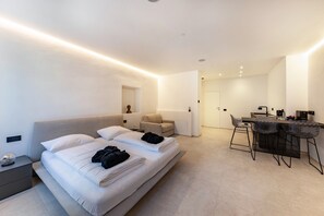 Une chambre d’hôtel moderne équipée d’un lit, d’une table de chevet, d’une chaise, d’un bureau et d’un coin bar.
