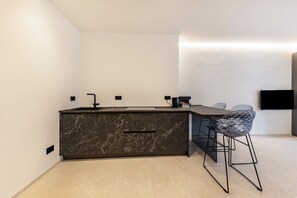 Cozinha moderna com ilha de mármore, banquetas e televisão de tela plana na parede.