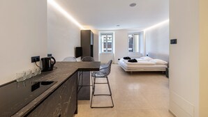 Cocina moderna con encimera oscura, cafetera y taburete de bar.
