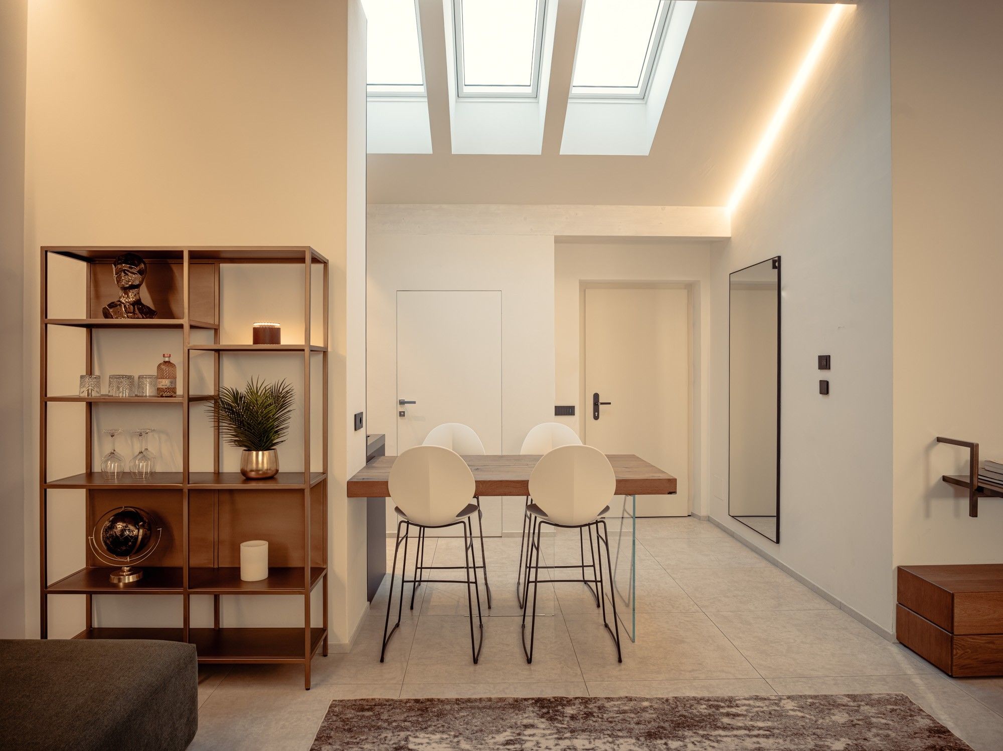 Ein modernes Interieur mit Essbereich, Bücherregal und einem Oberlicht.