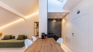 A modern interior with a wooden dining table, white chairs, a green sofa, and a dark accent wall. - Studio Apartment 'App 303 Palazzo Cavour' with Mountain View, Wi-Fi and Air Conditioning (Bolzano)
