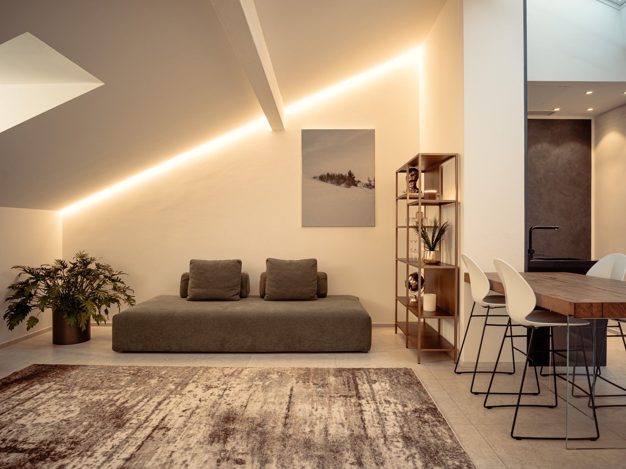 A modern living room with a sofa, a coffee table, a dining area with chairs, and a bookshelf.