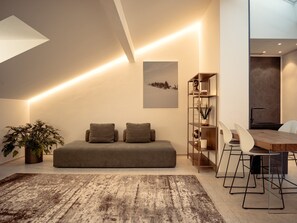 Un salon moderne comprenant un canapé, une table basse, un coin repas avec des chaises et une bibliothèque.