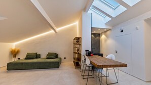 A modern loft bedroom with a skylight, a green sofa, a wooden dining table, and a minimalist decor. - Studio Apartment 'App 303 Palazzo Cavour' with Mountain View, Wi-Fi and Air Conditioning (Bolzano)
