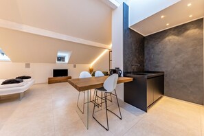 A modern kitchen with a dining area, a built-in oven, and a TV.