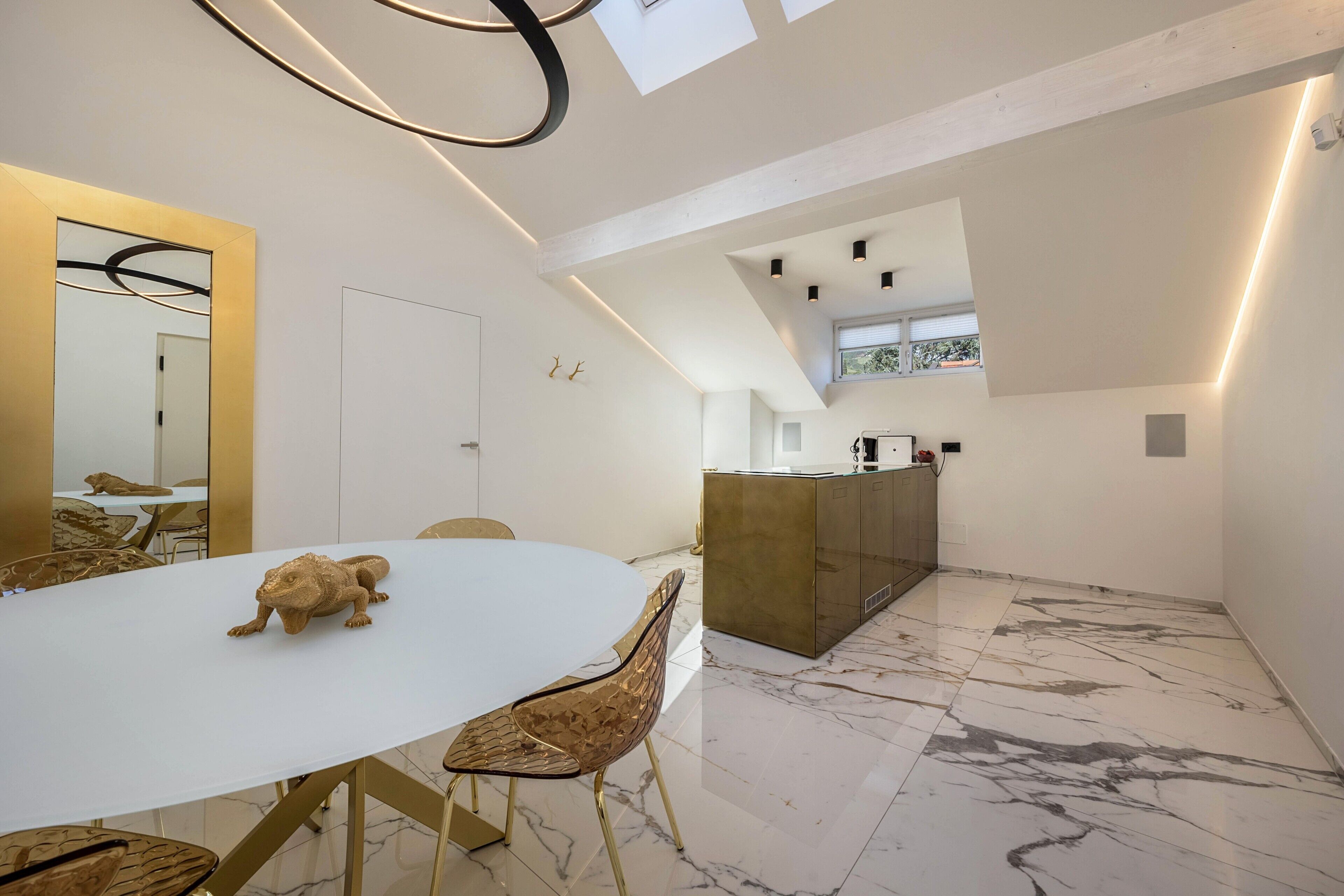 A modern dining area with a white table, gold chairs, and a small animal figurine.