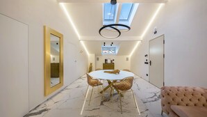 Een modern interieur met een marmeren vloer, een ronde eettafel met stoelen, een bank en een dakraam.