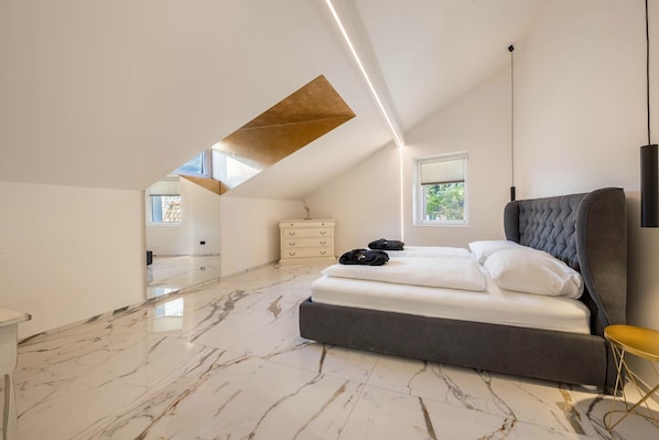 Une chambre à coucher moderne avec un grand lit, une commode et une fenêtre de toit.