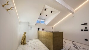 Een moderne keuken met een marmeren vloer, een eiland in goudkleur en een klein raam.