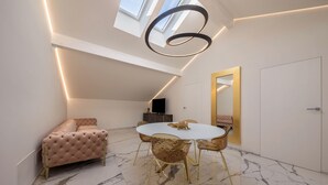 Een moderne kamer met een ronde eettafel, comfortabele zithoek, een grote spiegel en een dakraam.